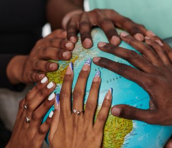 close up of diverse teenagers' hands delicately exploring a globe, capturing the essence of curiosity and exploration in their tactile engagement with geographical knowledge